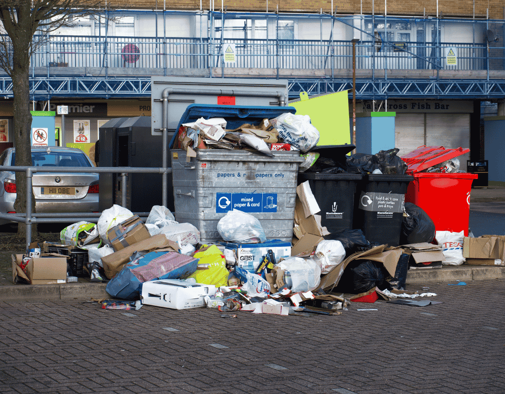 overflowing trash and recycling bins in commercial waste collection area