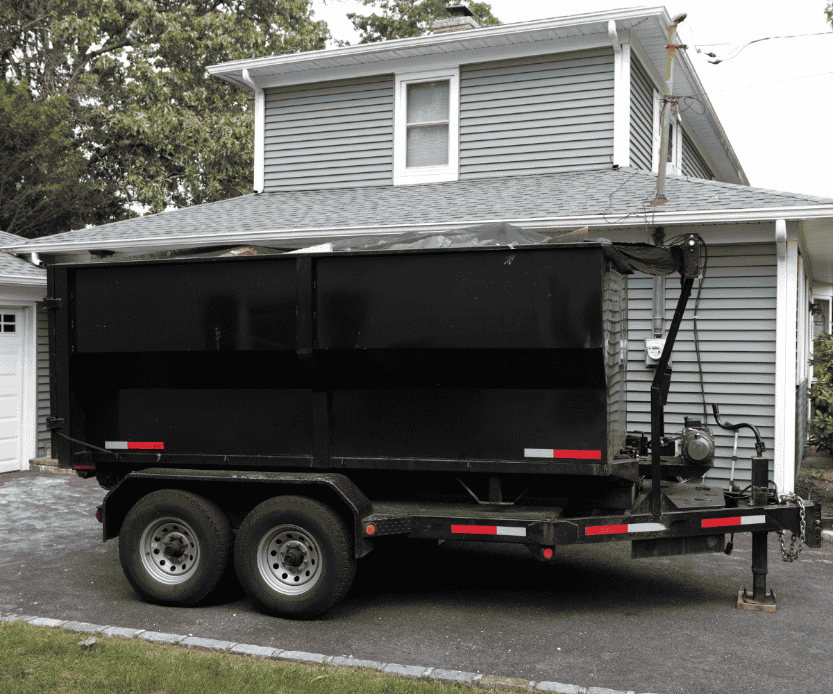black dumpster trailer parked outside residential home in El Paso County