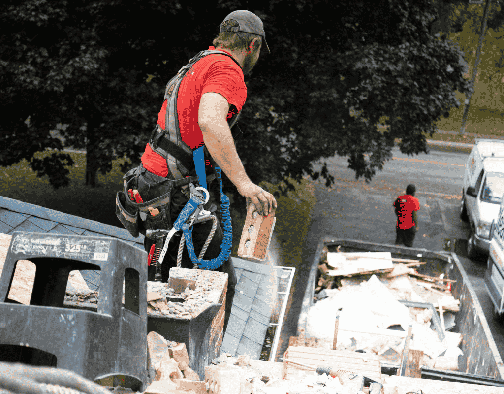 junk removal worker hauling construction debris into dumpster trailer